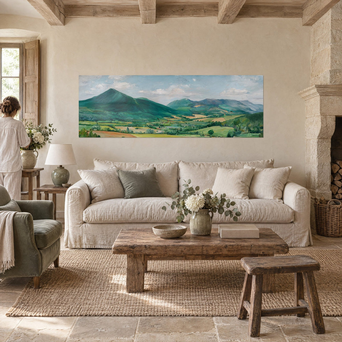 Wall art with an emerald green pyramidal peak dominating a valley of ochre fields, figures seen from behind, above a sofa in a bright living room