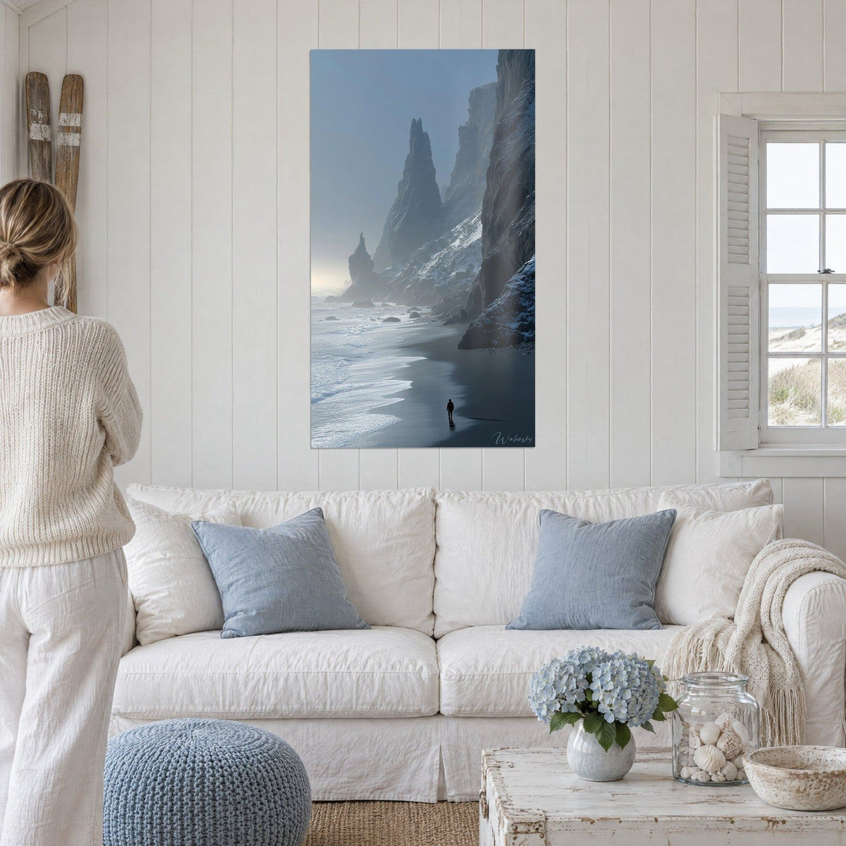 Wall art basalt cliffs shrouded in bluish mist, a silhouette on black sand, above a sofa in a bright living room