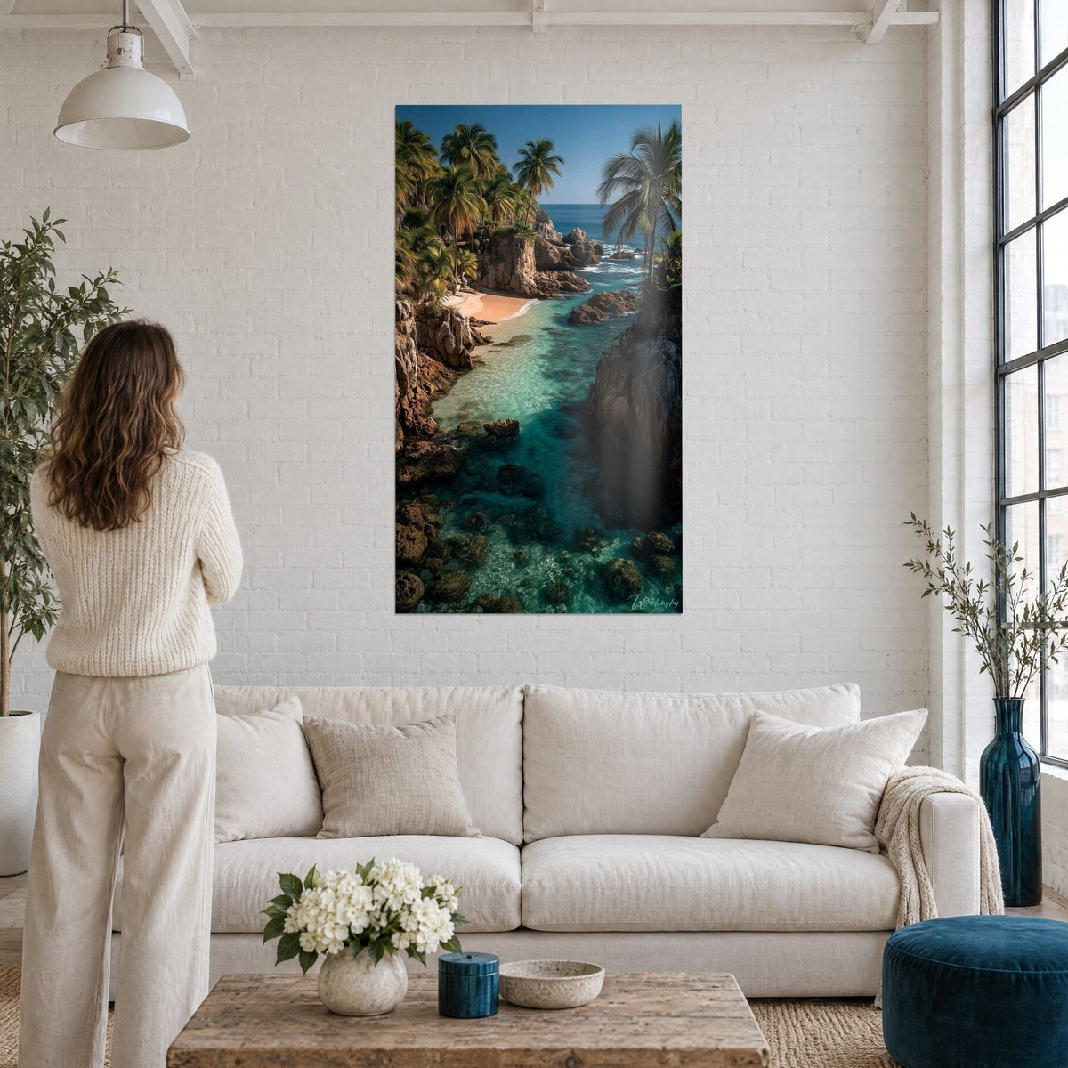 Tableau crique tropicale aux eaux turquoise et sable ocre, palmiers vert vif, au-dessus d'un canapé dans un salon lumineux