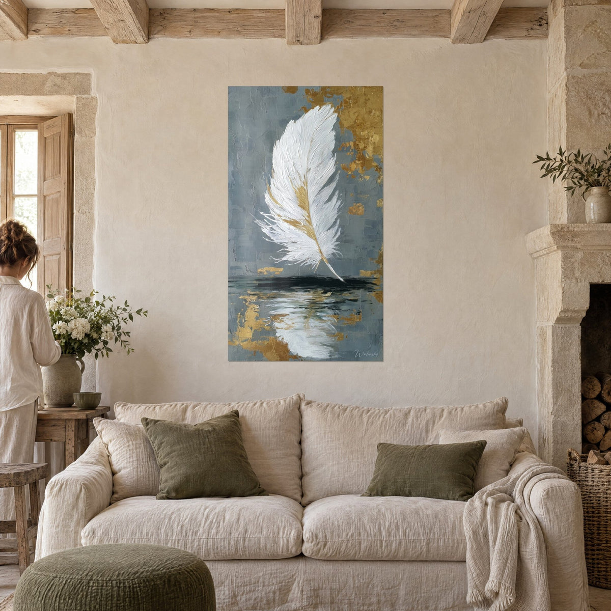 Tableau plume blanche effilée aux nervures dorées sur fond gris-bleu, au-dessus d'un canapé dans un salon lumineux