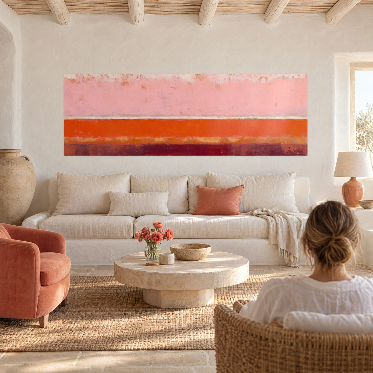 Tableau abstrait en bandes rose poudré et orange vif, femme de dos au-dessus d'un canapé dans un salon lumineux