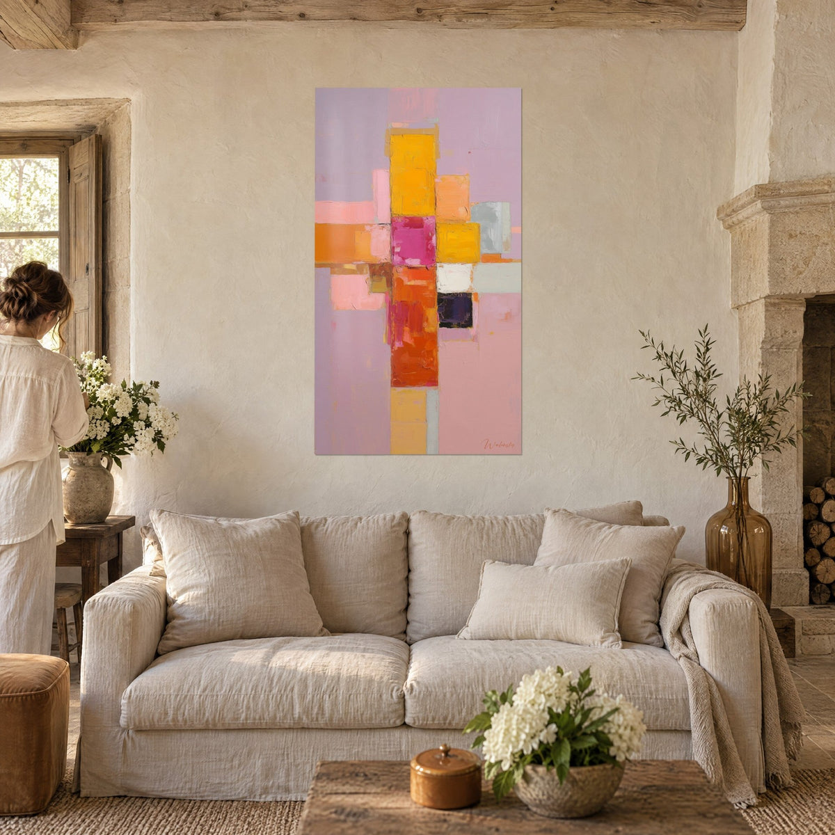 Cuadro abstracto de cuadrados apilados en amarillo mostaza y magenta sobre fondo lila, una mujer de espaldas, sobre un sofá en un salón luminoso
