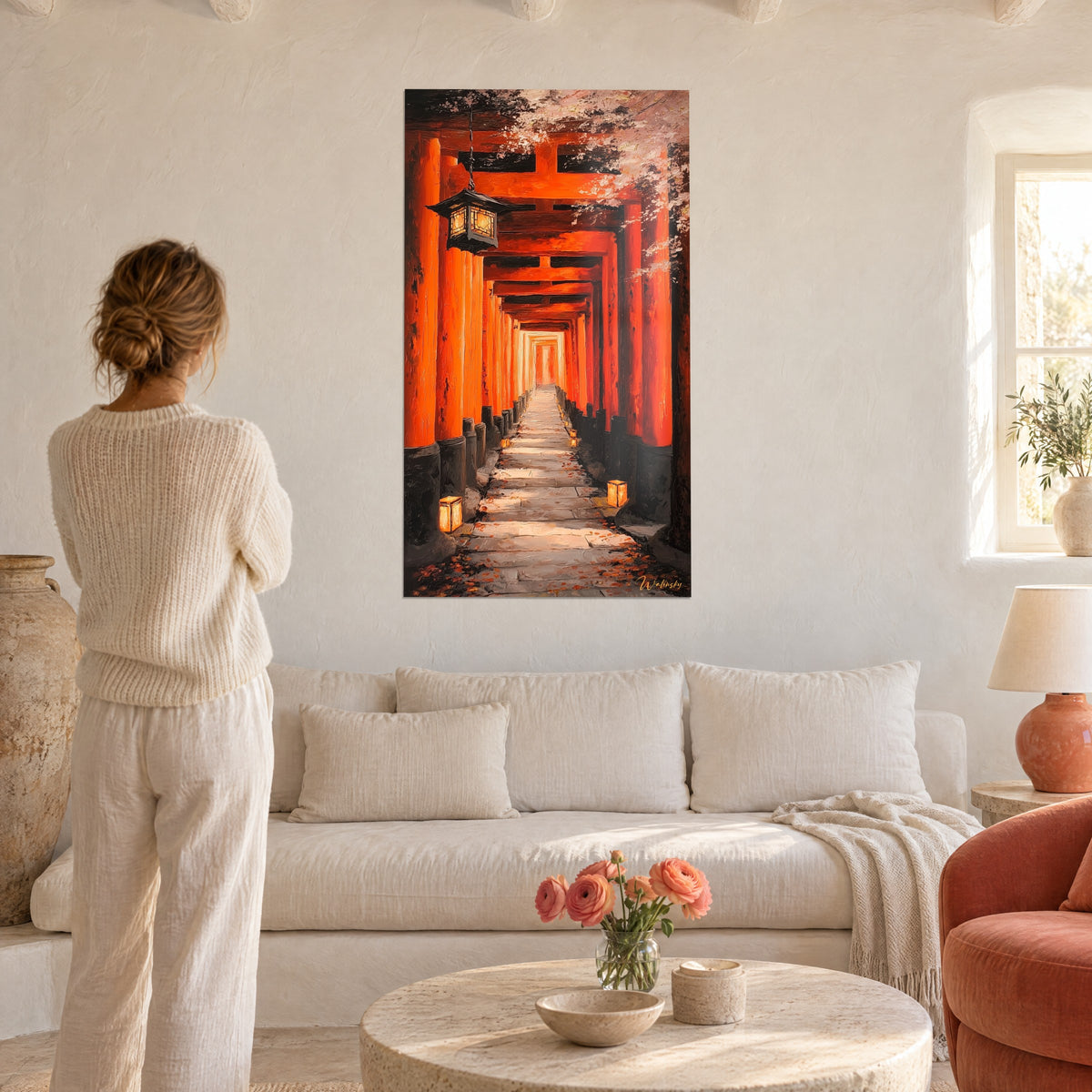 Πίνακας τούνελ από torii βερμιλιόν, κρεμαστό σιδερένιο φανάρι και ροζ κλαδιά κερασιάς, γυναίκα από πίσω πάνω από καναπέ σε φωτεινό σαλόνι