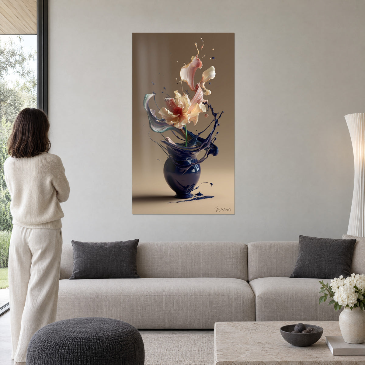 Tableau fleur rose et crème jaillissant d'un vase indigo, éclaboussures marine sur fond taupe, au-dessus d'un canapé dans un salon lumineux