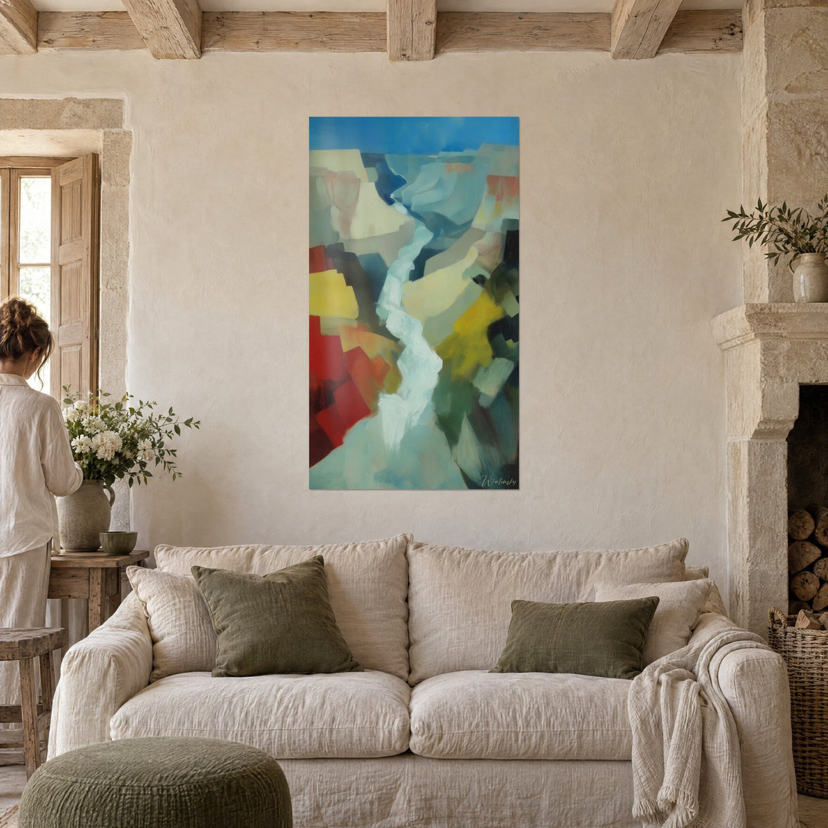 Quadro canyon astratto con blocchi rossi, gialli e ocra, fiume turchese sinuoso, persona di spalle sopra un divano in un soggiorno luminoso