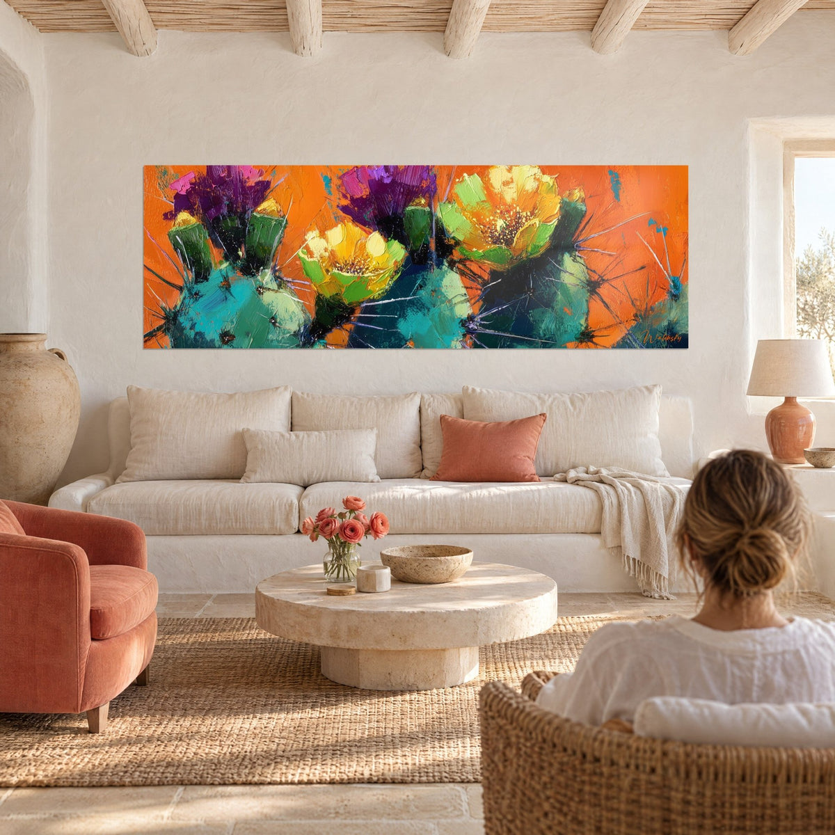 Gemälde Kakteen in gelben Blüten Sonnengelb und Anisgrün auf leuchtend orangefarbenem Hintergrund, Frau von hinten, über einem Sofa in einem hellen Wohnzimmer