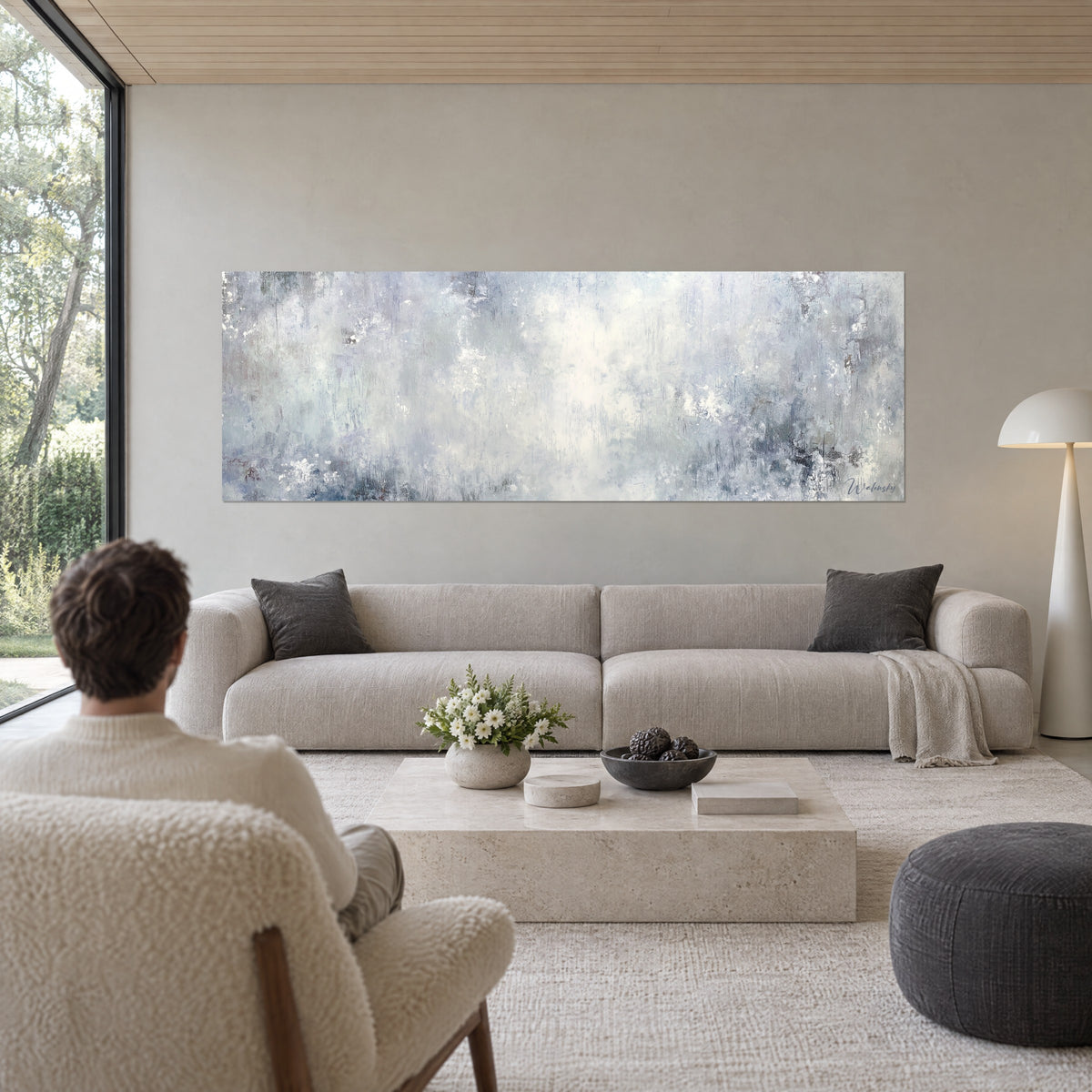 Quadro con foschia azzurrata dai riflessi madreperlacei, grigio perla e bianco crema, visto di spalle da una coppia sopra un divano in un soggiorno luminoso