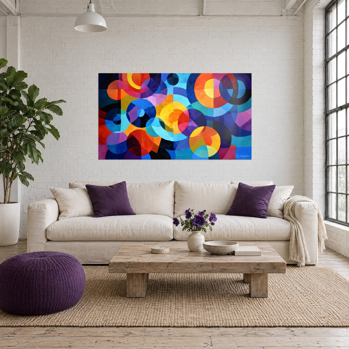 Wall art with overlapping orange, yellow and cobalt blue circles in vivid tones, hanging above a sofa in a bright living room