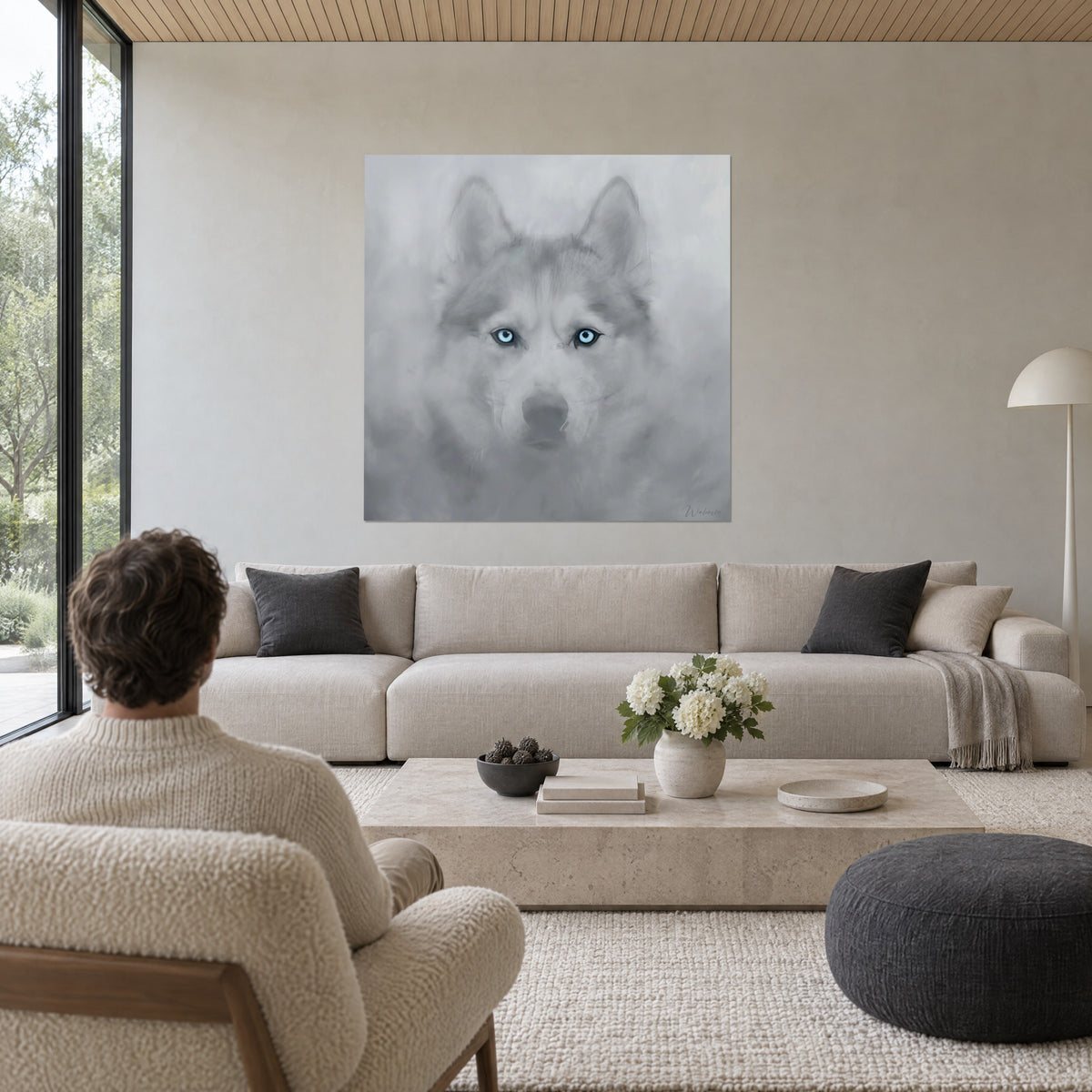 Obraz husky o lodowoniebieskich oczach, perłowoszarym futrze i białej mgle, kremowa ściana, mężczyzna tyłem, nad sofą w jasnym salonie