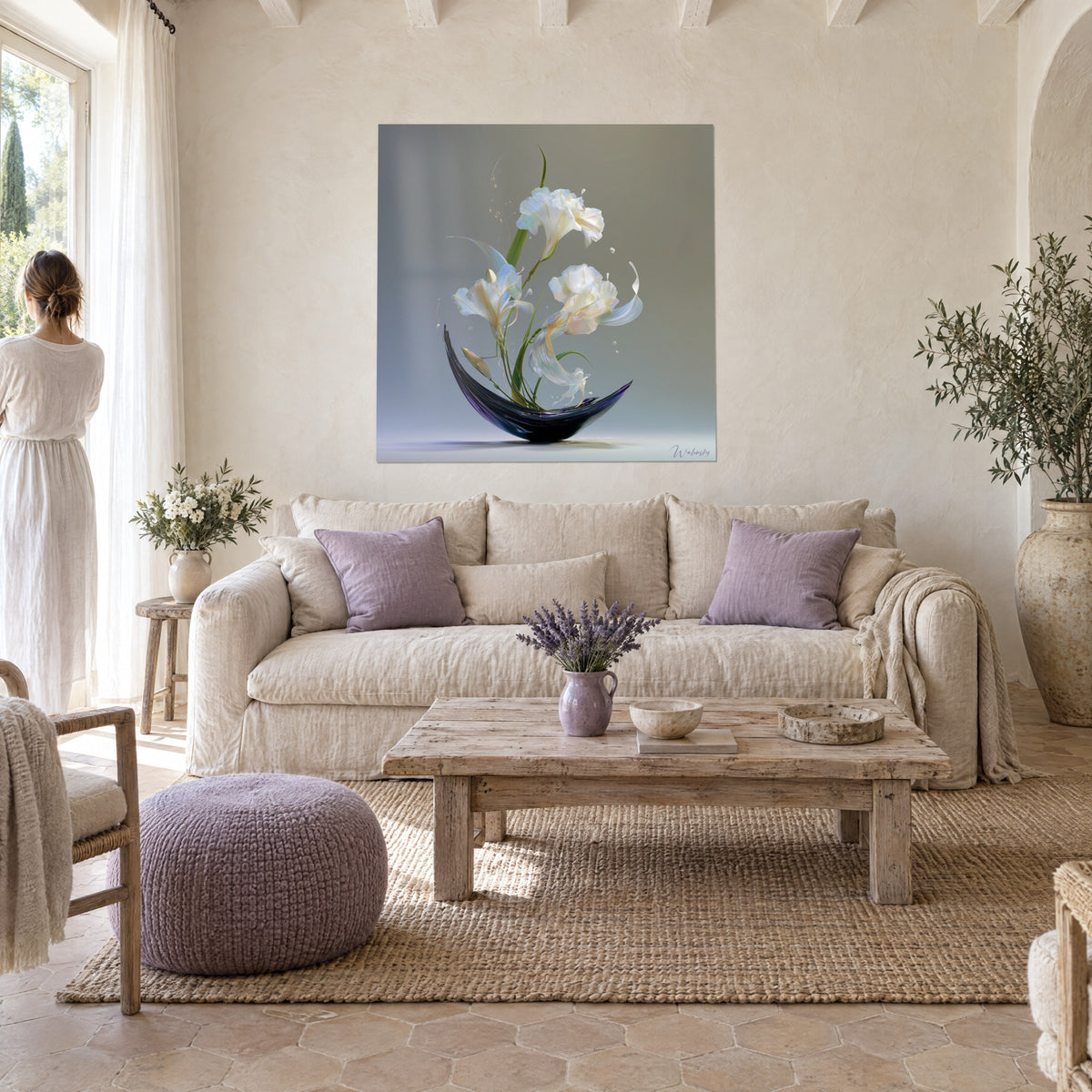 Tableau lys blancs nacrés jaillissant d'un vase noir en croissant, fond gris-vert, au-dessus d'un canapé dans un salon lumineux