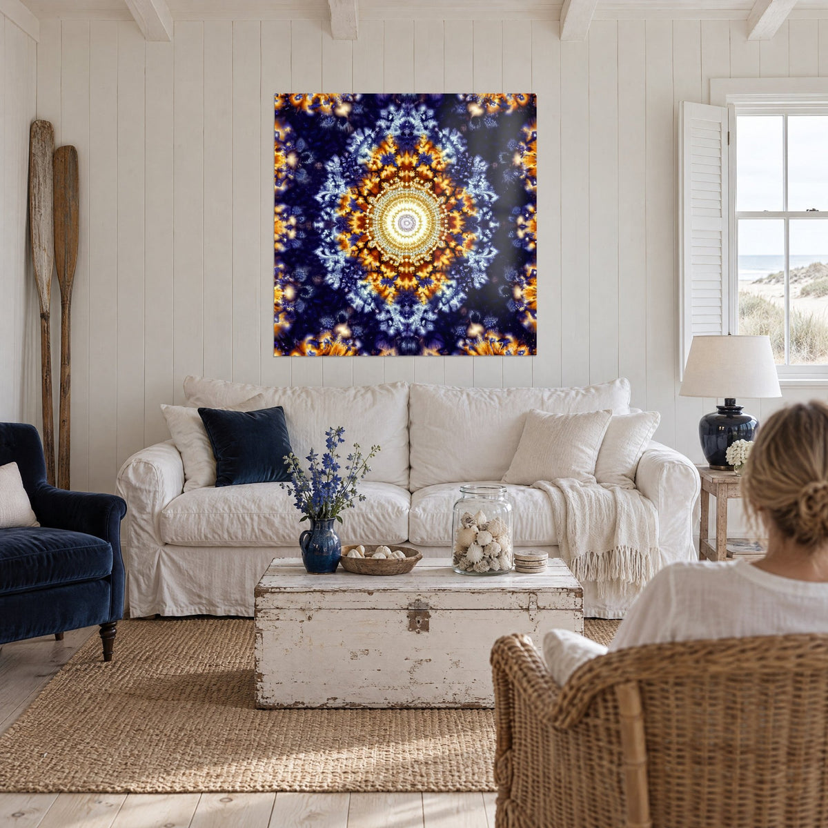 Gemälde mit fraktalem Mandala, bernsteinfarbene Blütenblätter um ein elfenbeinweißes Herz auf indigoblauem Grund, über einem Sofa in einem hellen Wohnzimmer