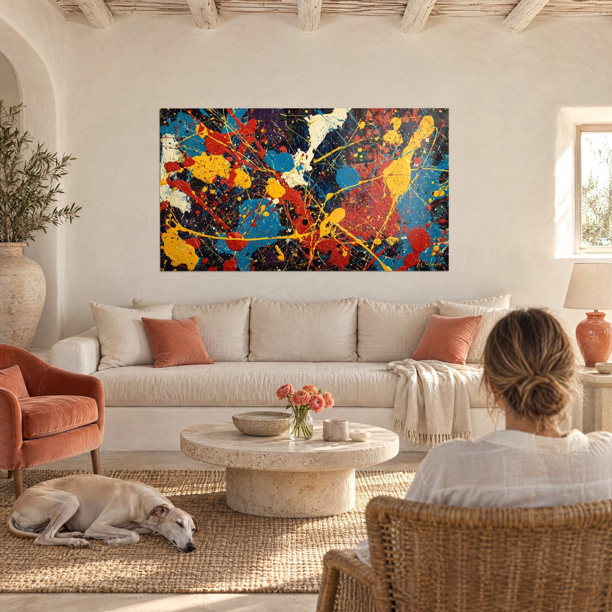 Wall art with yellow and red splashes on a midnight blue background, woman from behind and a greyhound, above a sofa in a bright living room
