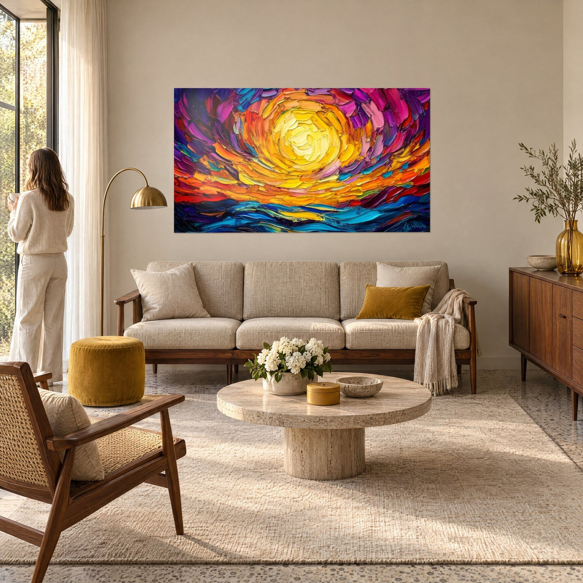 Schilderij met een citroengele spiraalzon in oranje tinten, paarse lucht en blauwe golven, een vrouw van achteren boven een bank in een lichte woonkamer