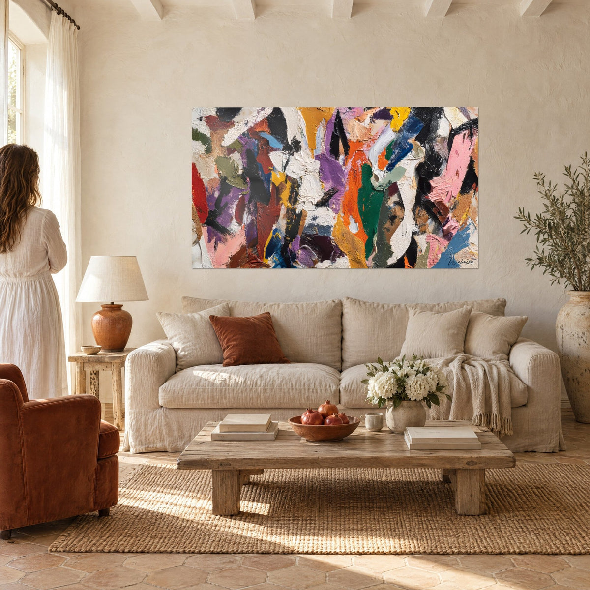Wall art with orange, violet and emerald green palette-knife strokes, couple seen from behind in front, above a sofa in a bright living room