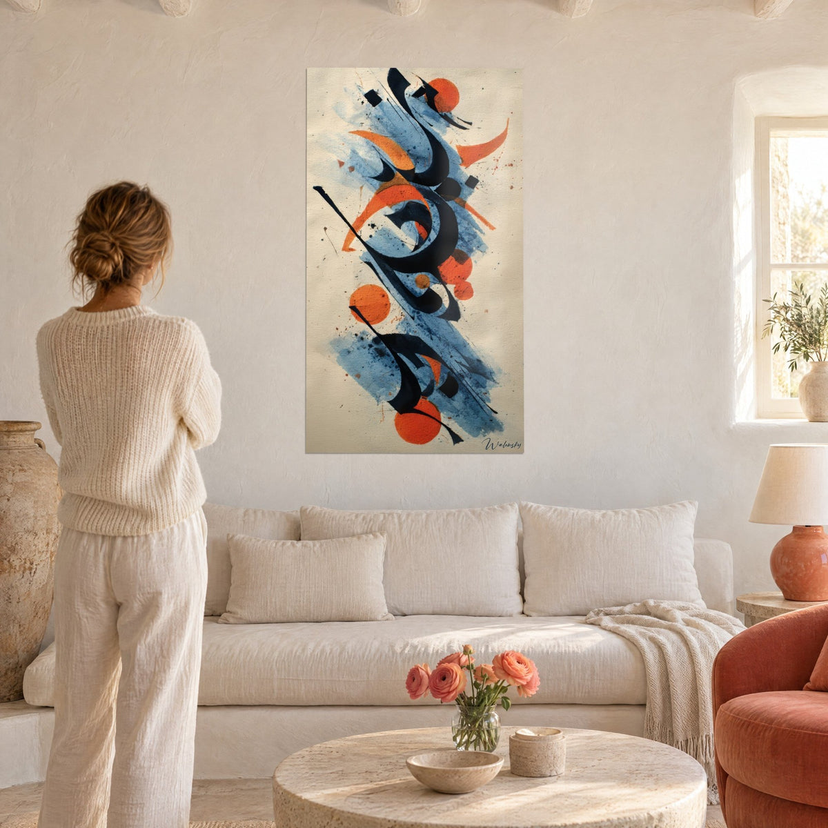 Wall art abstract calligraphy with black ink strokes and orange discs, blue wash, woman seen from behind, above a sofa in a bright living room