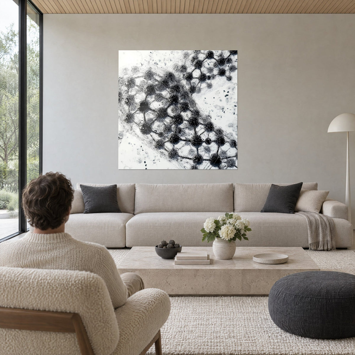 Cuadro doble hélice de ADN en hebras negras sobre fondo blanco crema, hombre de espaldas, encima de un sofá en un salón luminoso