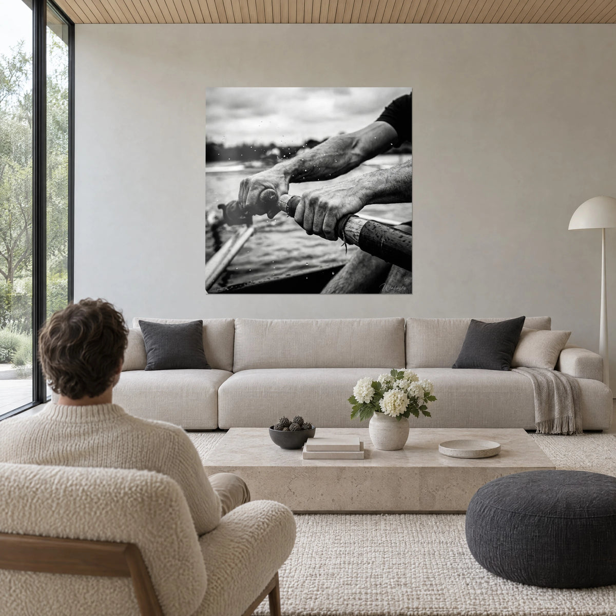 Cuadro manos de remero agarrando remos de madera, blanco y negro, gotas de agua, encima de un sofá en un salón luminoso