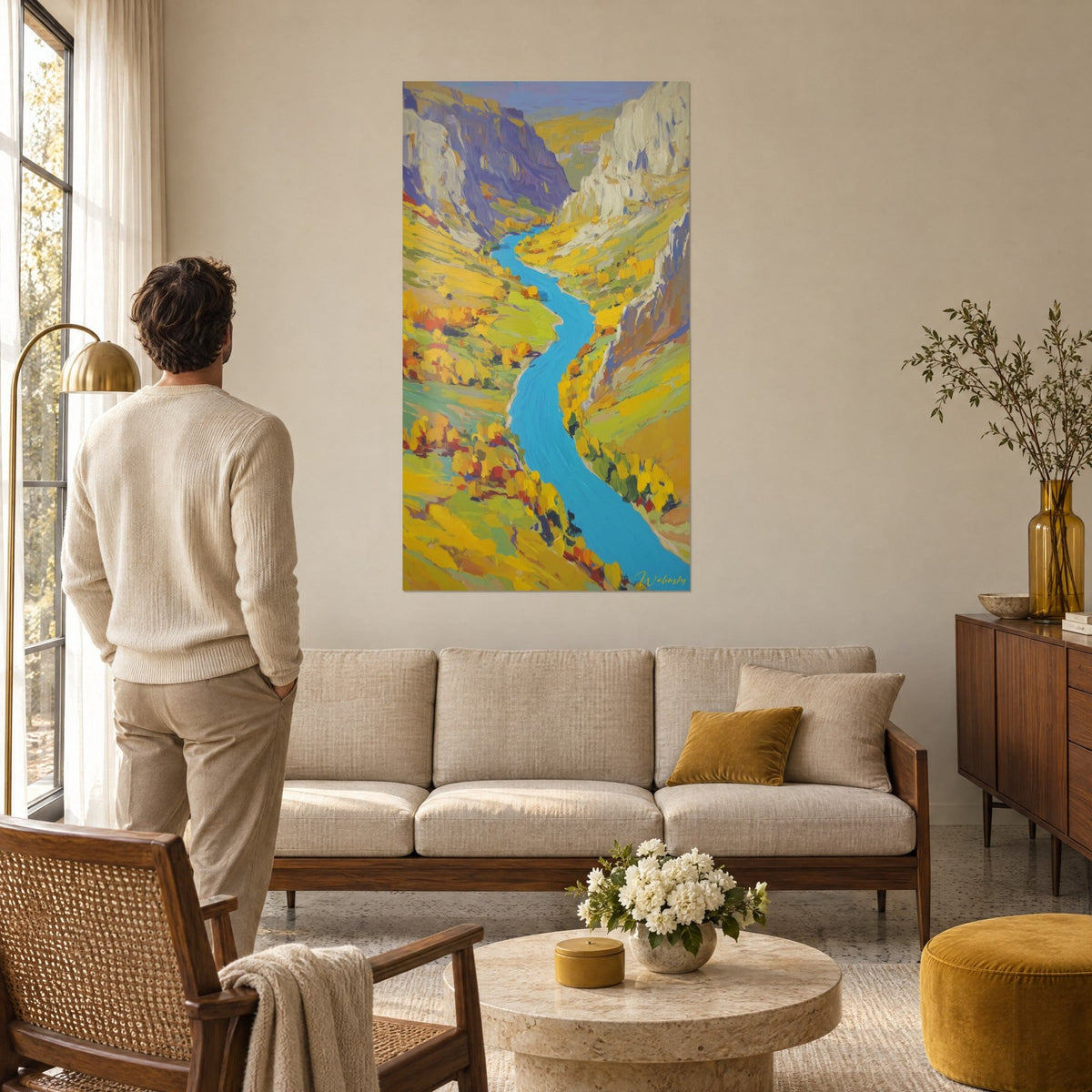 Wall art turquoise river winding between mauve cliffs and yellow meadows, hanging above a sofa in a bright living room