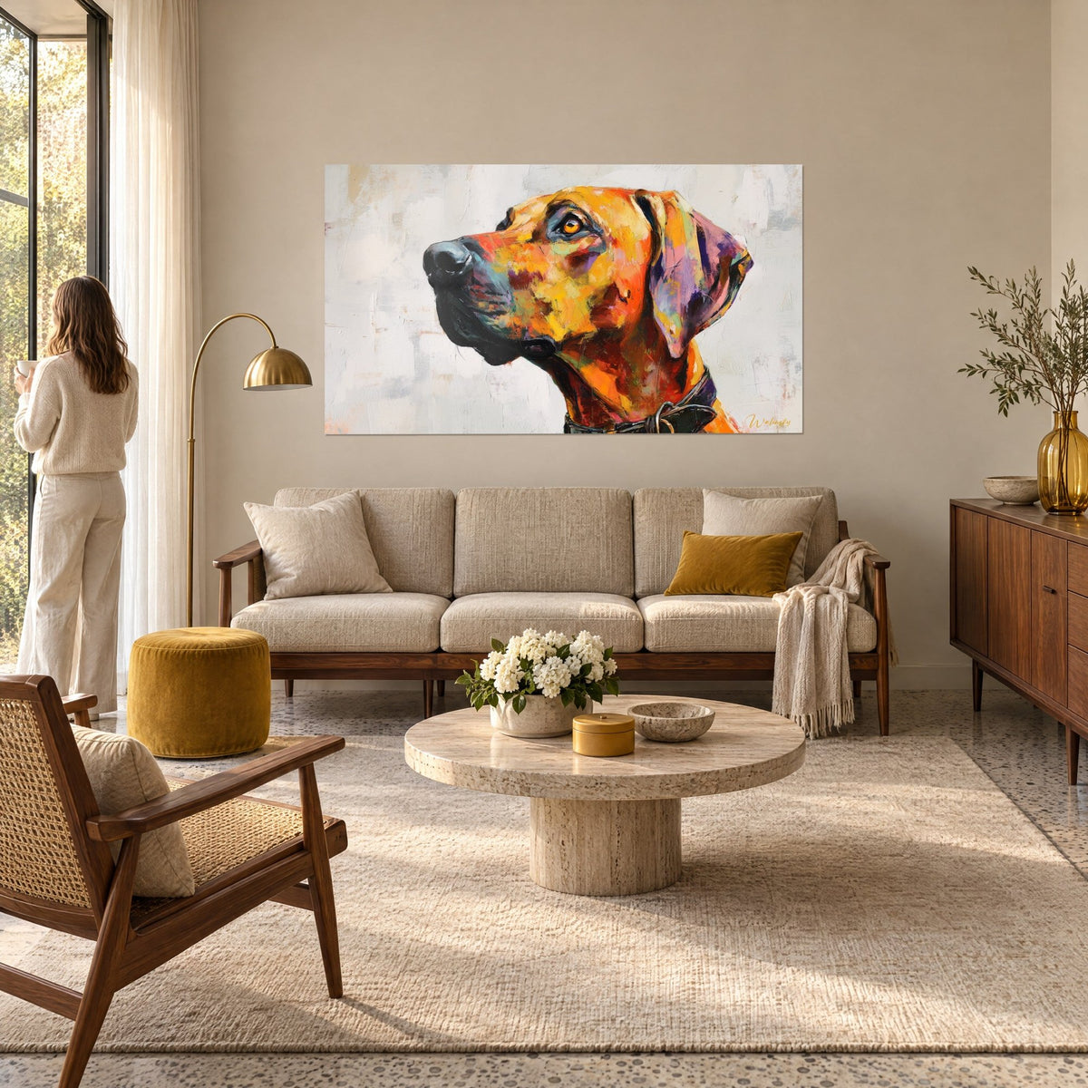 Πίνακας Rhodesian Ridgeback ζωγραφισμένος σε πορτοκαλί και μωβ αποχρώσεις, με κεχριμπαρένιο βλέμμα στραμμένο προς τα πάνω, γυναίκα από πίσω πάνω από έναν καναπέ σε φωτεινό σαλόνι