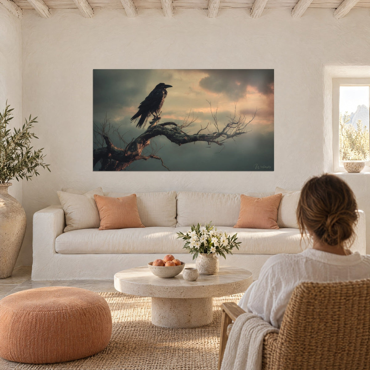 Wall art black raven perched on a dead branch, grey and pink twilight sky, above a sofa in a bright living room