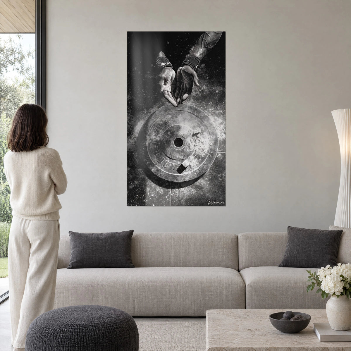 Schilderij handen bestoven met magnesium boven een gietijzeren schijf, zwart en grijs, beige bank, hangend boven een bank in een lichte woonkamer