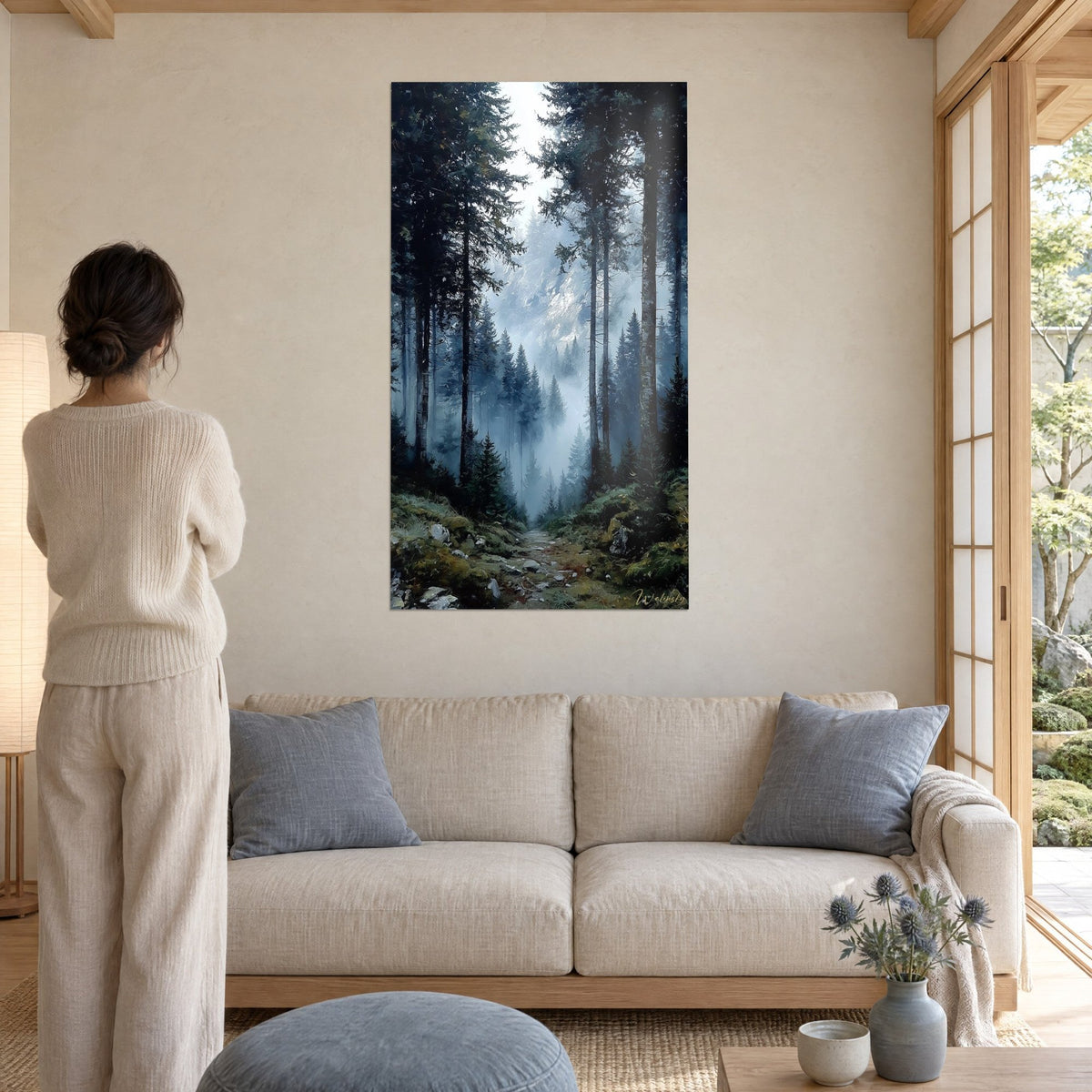 Tableau sapins élancés dans la brume bleutée, sentier moussu vert olive, femme de dos, au-dessus d'un canapé dans un salon lumineux