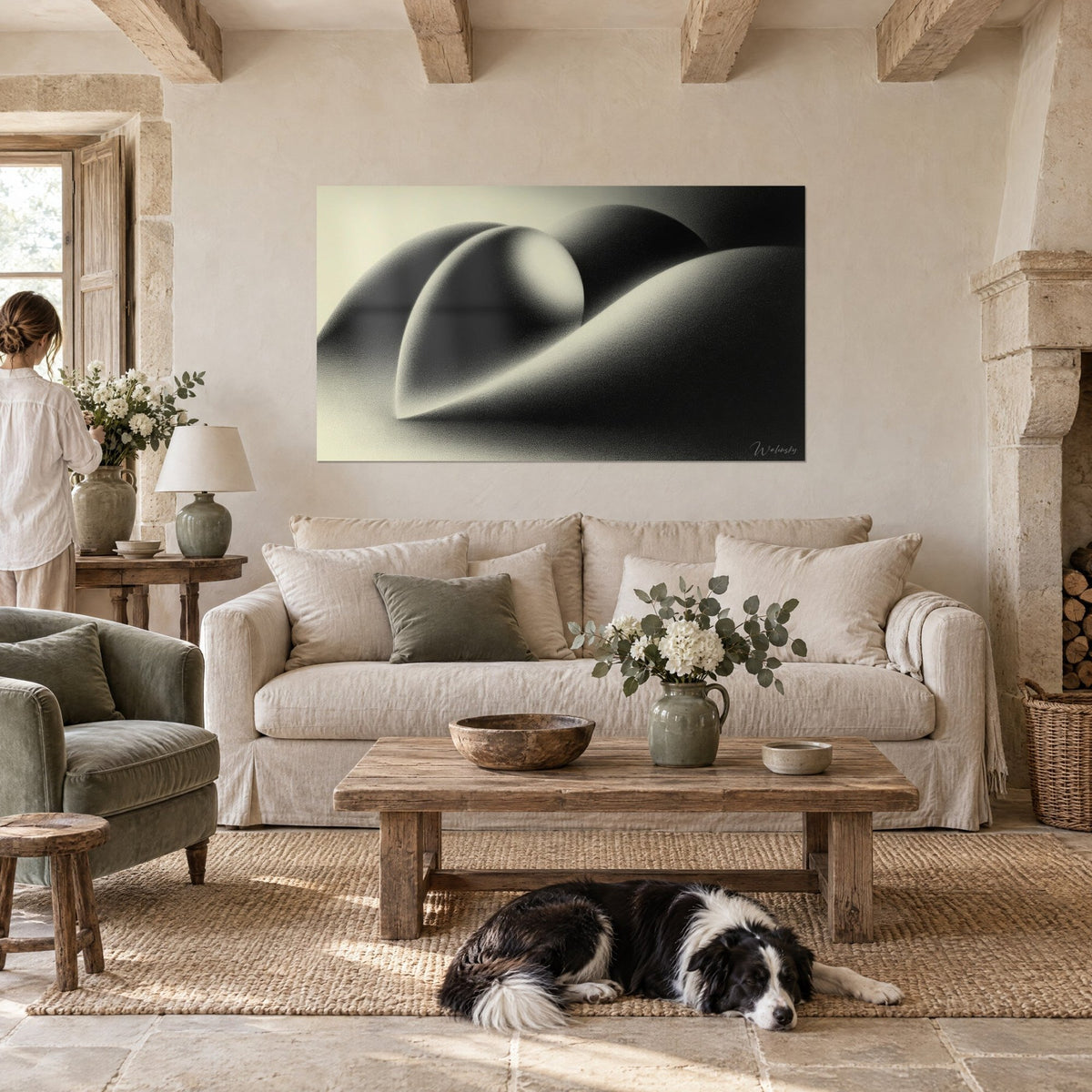 Tableau formes organiques en dégradé noir et ivoire, courbes de galets lisses, collie couché, au-dessus d'un canapé dans un salon lumineux
