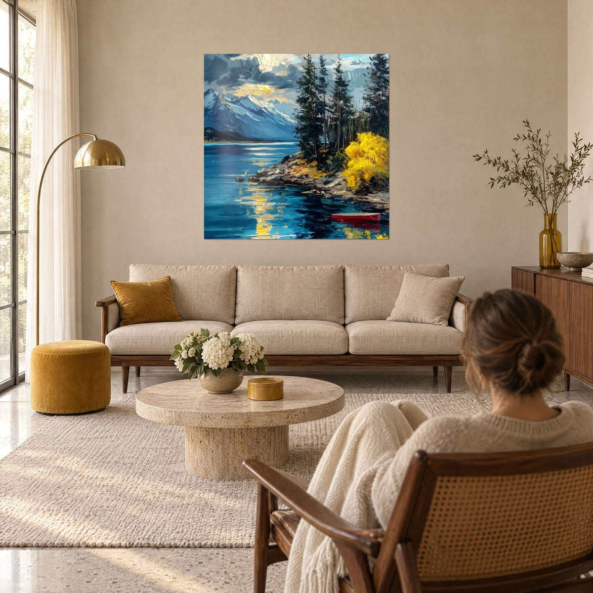 Quadro lago alpino dalle acque turchesi, arbusto giallo vivo e barca rossa, una donna di spalle sopra un divano in un soggiorno luminoso