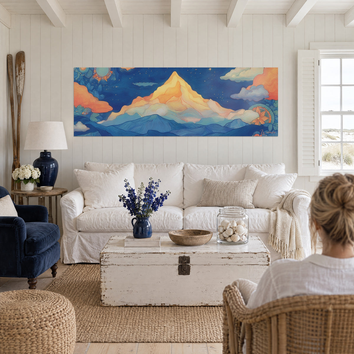 Schilderij met een gouden piramidevormige top onder een middernachtblauwe sterrenhemel, koraalkleurige wolken, twee personen van achteren, boven een bank in een lichte woonkamer