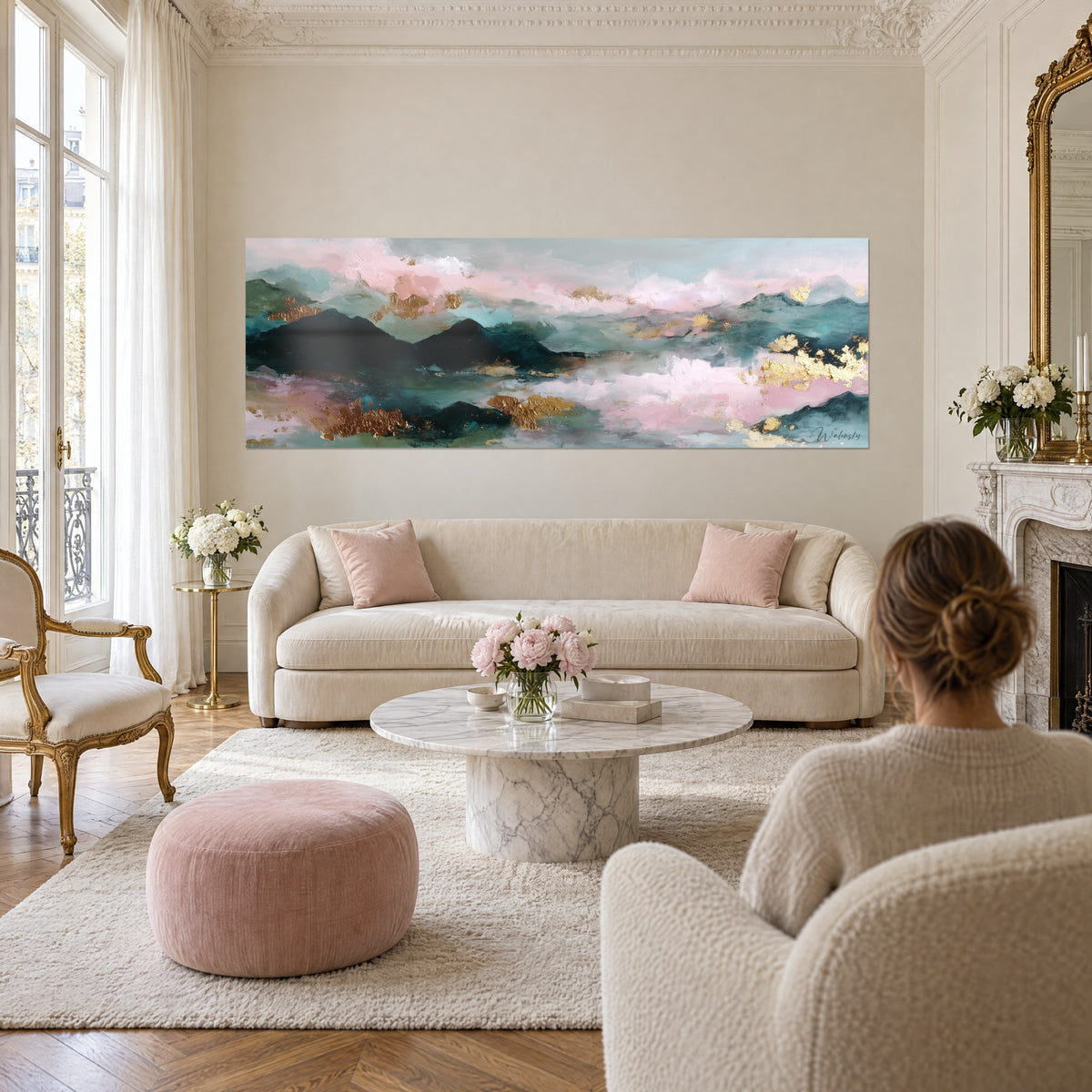 Schilderij van nevelige bergen in poederroze en dennengroen met gouden accenten, boven een bank in een lichte woonkamer