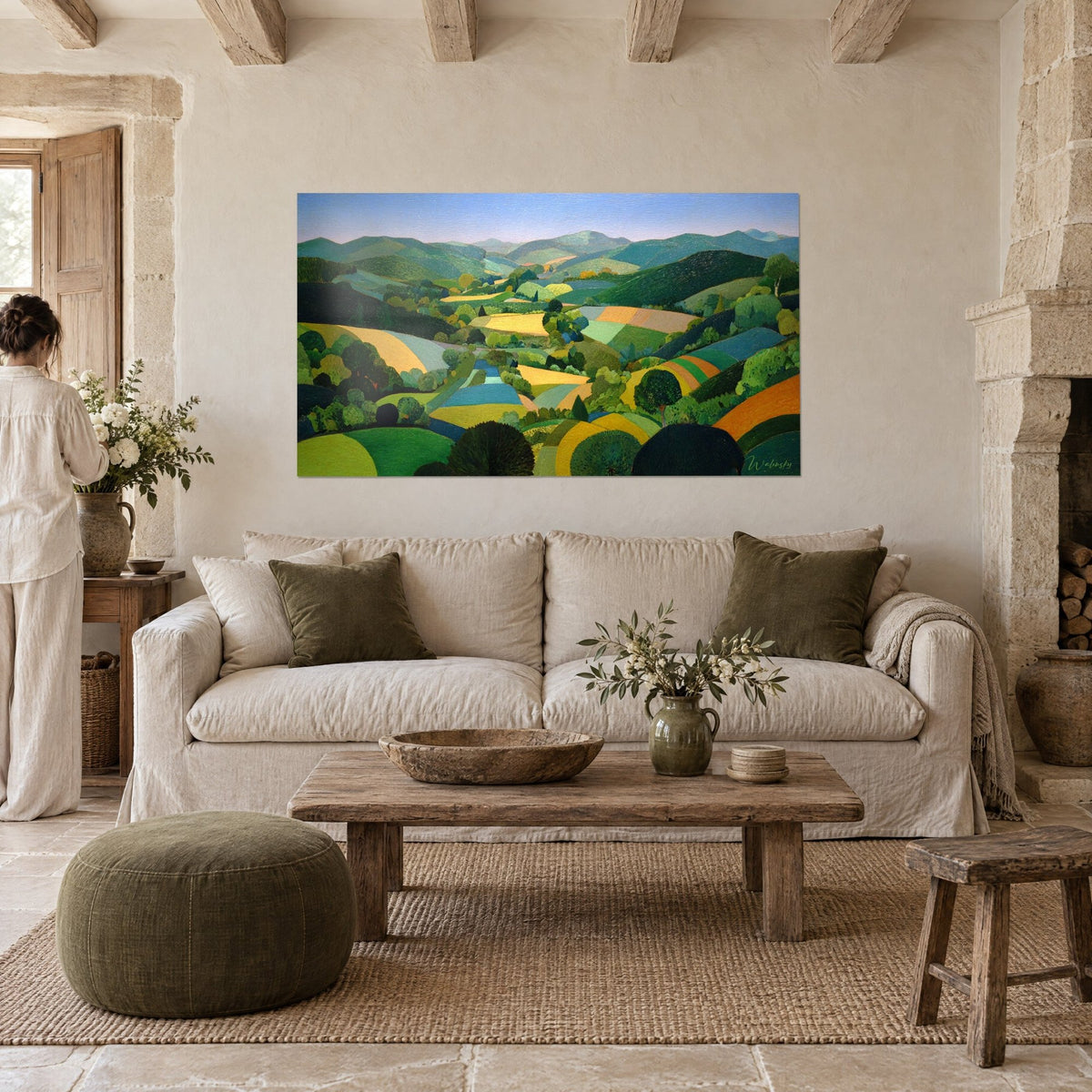 Tableau paysage vallée verdoyante, champs vert tilleul et jaune moutarde, une femme de dos, au-dessus d'un canapé dans un salon lumineux