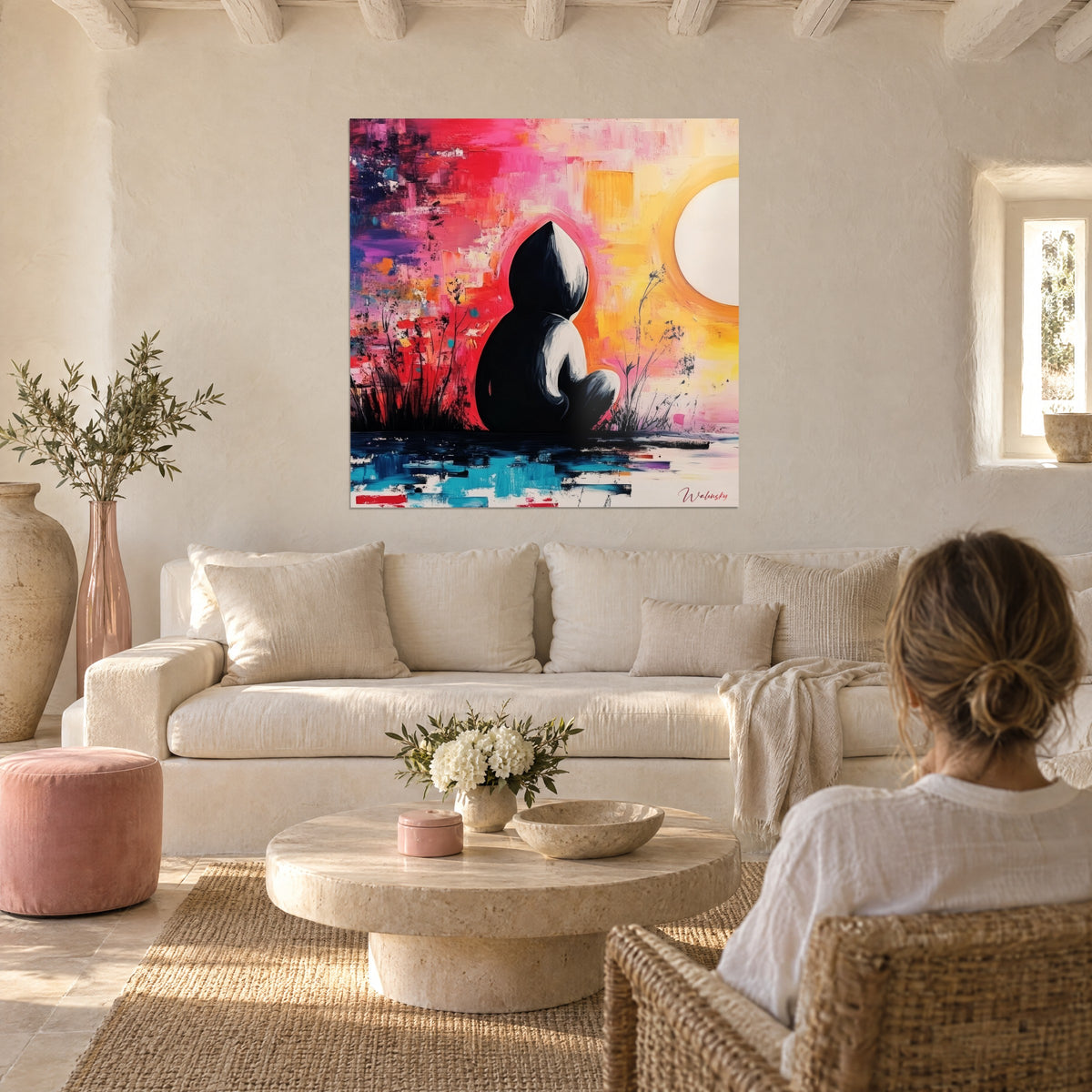Gemälde schwarze Silhouette sitzend vor einer weißen Sonne, rosa Hintergrund, Rot und Gelb, über einem Sofa in einem hellen Wohnzimmer