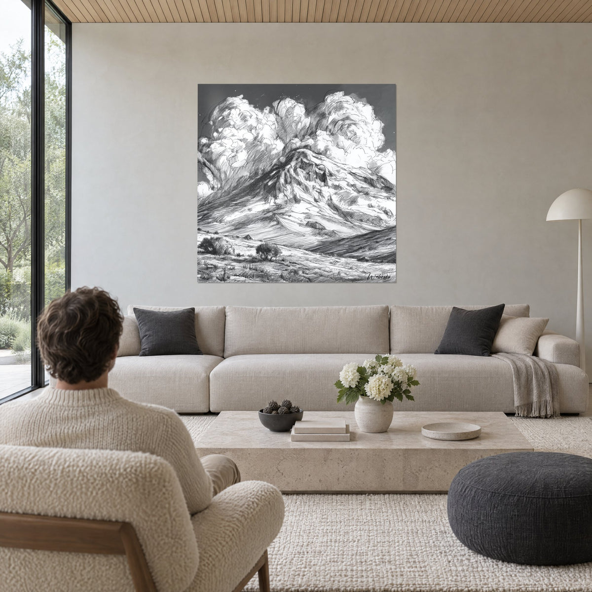 Wall art smoking mountain drawn in black and white ink, above a sofa in a bright living room