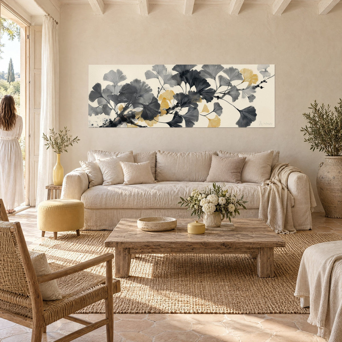 Schilderij met waaiervormige ginkgobladeren in antraciet grijs en goud op een inktlijn tak, boven een bank in een lichte woonkamer