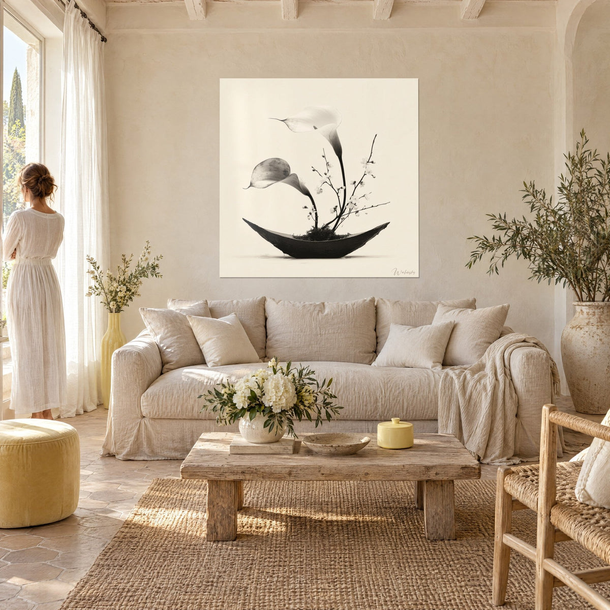 Gemälde Ikebana monochrom mit zwei weißen Calla auf cremefarbenem Hintergrund, schlanke schwarze Schale, über einem Sofa in einem hellen Wohnzimmer