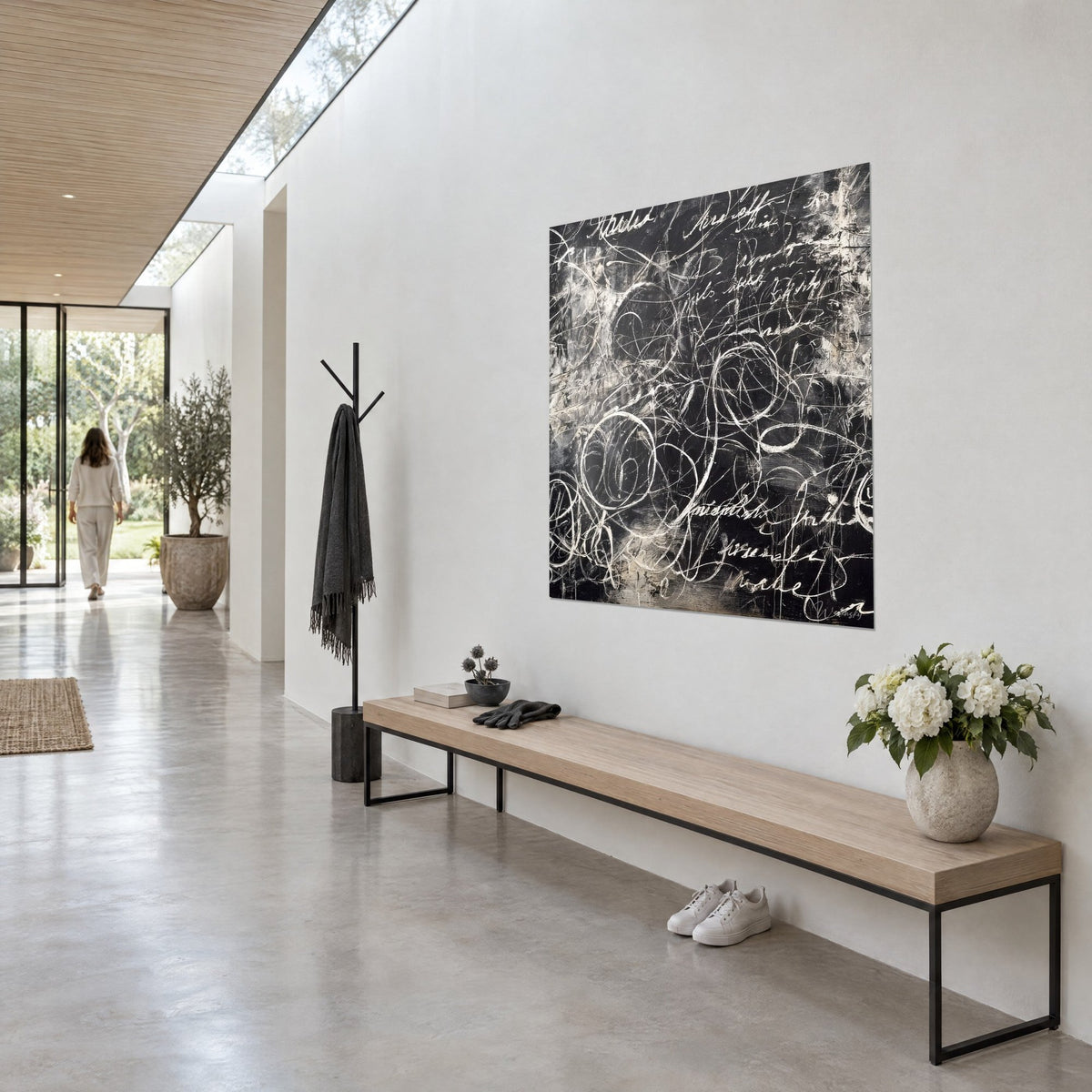 Wall art with abstract writing in ivory chalk spirals on charcoal black, three-quarter view, wooden bench, glazed corridor