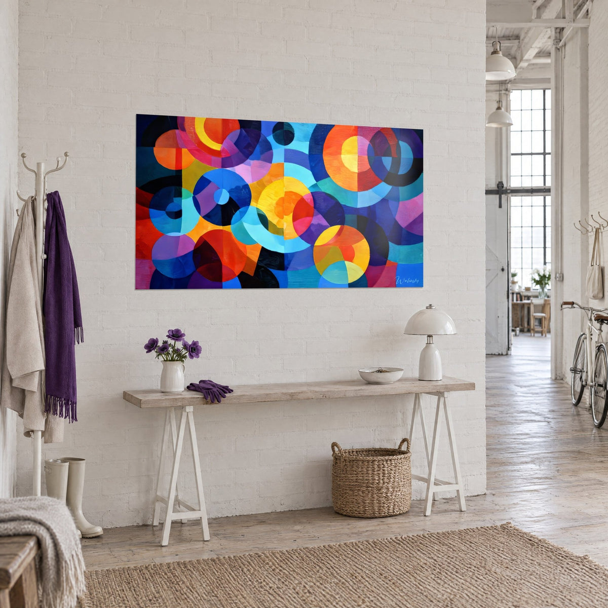 Wall art with a mosaic of turquoise and coral red rings with violet facets, hung above a wooden console in a bright loft