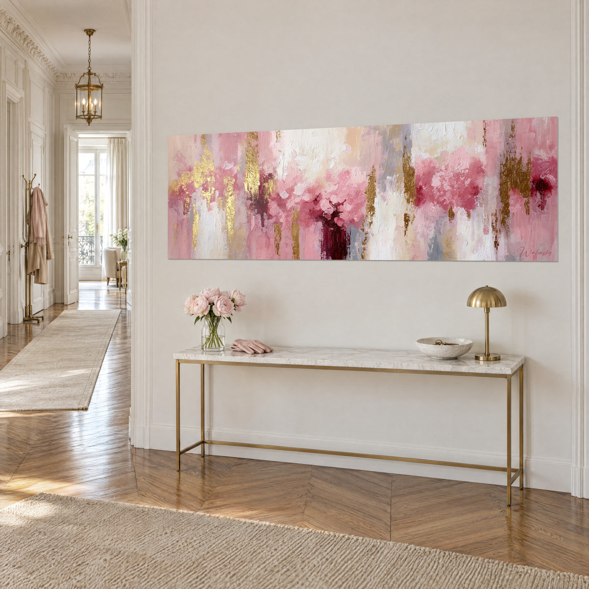 Cuadro panorámico de flores vaporosas en rosa y oro, burdeos en el centro, sobre una pared blanca encima de una consola dorada en París