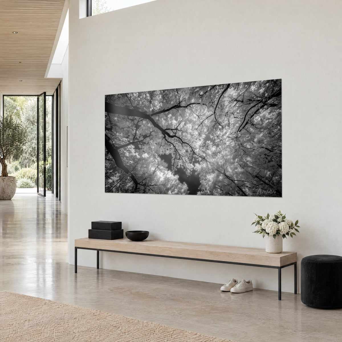 Tableau canopée infrarouge vue d'en bas, troncs noirs et feuilles blanches éclatantes, sur un mur beige près d'une baie vitrée