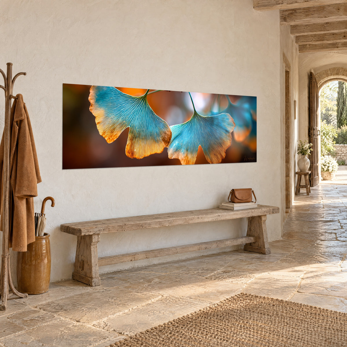 Quadro panoramico di due fronde di ginkgo che sfumano dal blu laguna all'ambra, sfondo ramato sfocato, sopra una panca in legno grezzo