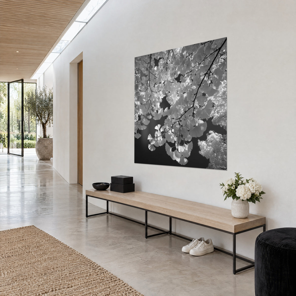 Schilderij met tegenlicht op ginkgotakken, lichtgevende witte bladeren op antracietkleurige achtergrond, opgehangen in een lichte gang