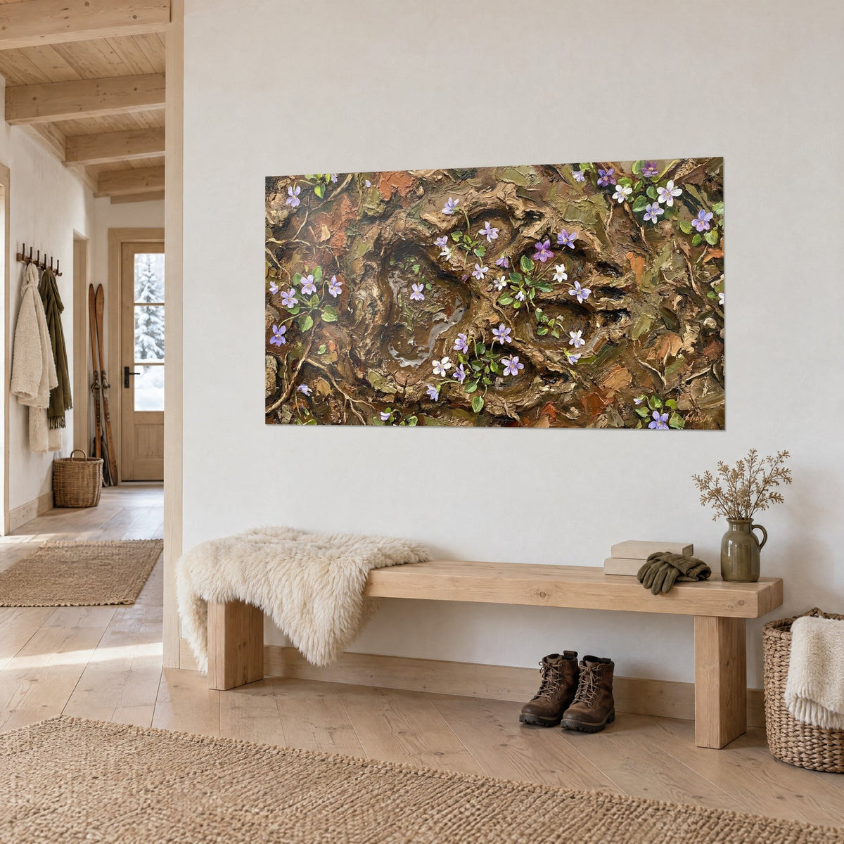 Cuadro de pétalos malva y blancos sobre suelo de humus rojizo, huellas de barro en relieve, encima de un banco de madera en la entrada de un chalet