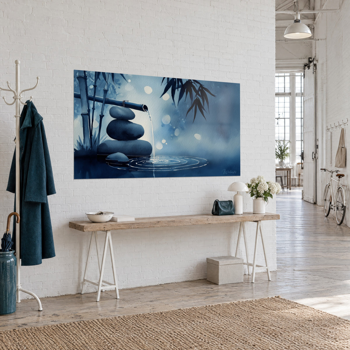 Zen watercolour wall art: three balanced pebbles, indigo bamboo leaves and steel-blue concentric ripples, three-quarter view in a loft