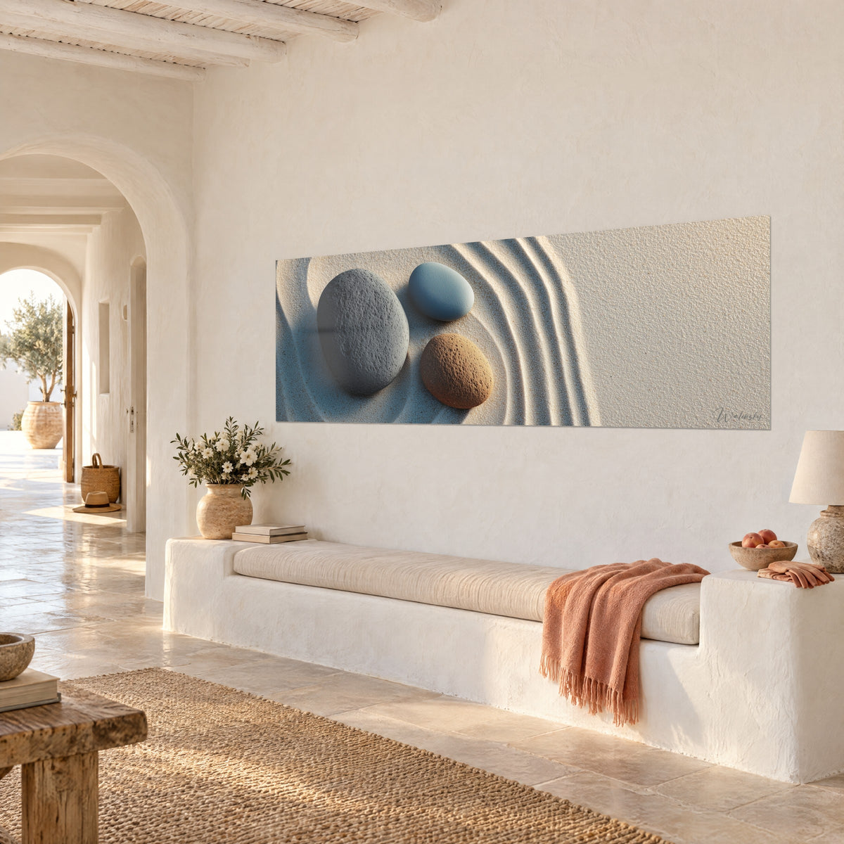 Quadro di tre pietre lisce, ardesia, azzurro cielo e ocra, circondate da solchi di sabbia, parete in calce bianca, panca mediterranea