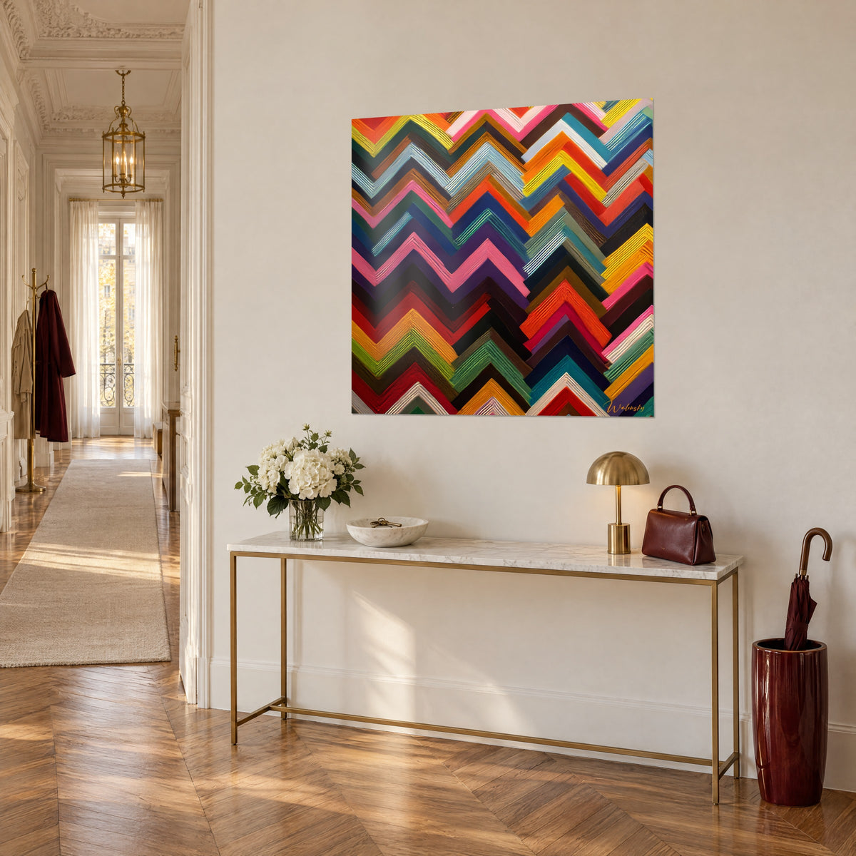 Wall art zigzags painted in bands of cobalt, saffron yellow and red, hung above a gilded console in a Haussmann-style entrance hall