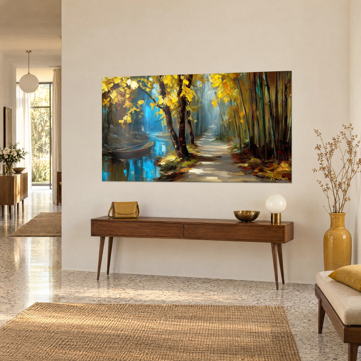 Schilderij herfstpad omzoomd met donkere boomstammen, felgele bladeren en een turquoise rivier, opgehangen aan een beige huismuur