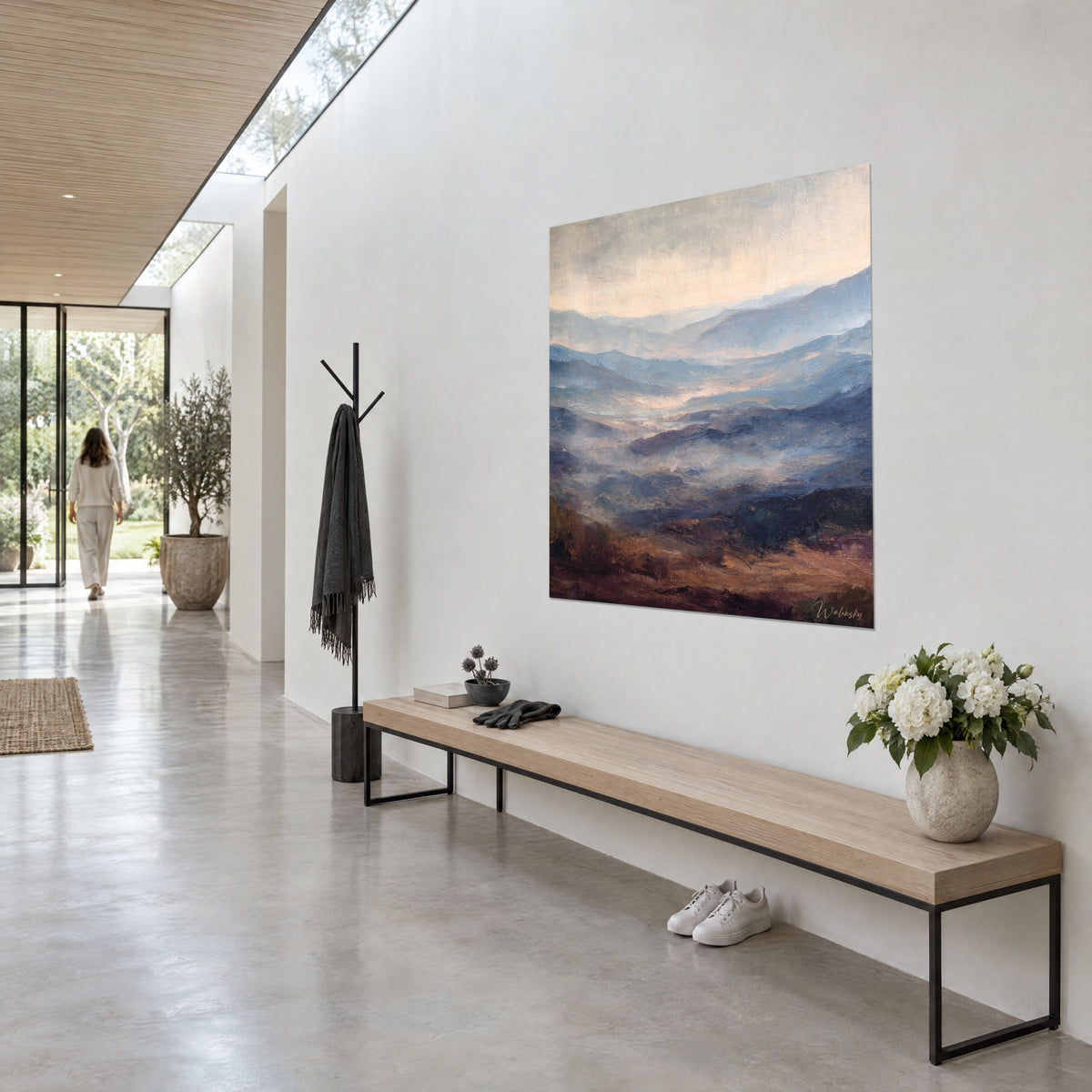 Gemälde Hügelkette im lila und blauen Dunst vor beige-rosa Himmel, hängend in einem hellen Flur