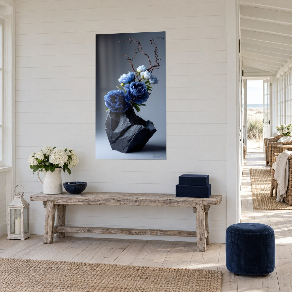 Tableau composition ikebana de fleurs indigo et blanches, branche sombre, pierre noire, mur lambrissé blanc, console en bois, bord de mer