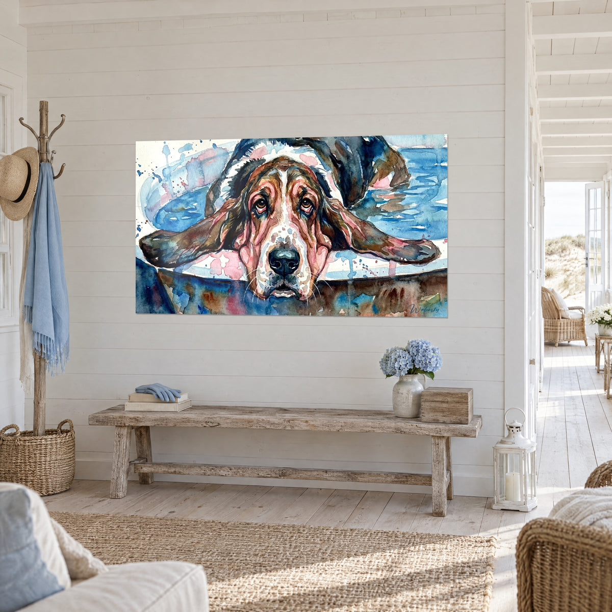 Cuadro de un perro de ojos tristes y hocico negro, manchas rosas y azules, visto de tres cuartos sobre una pared blanca de madera de una casa junto al mar