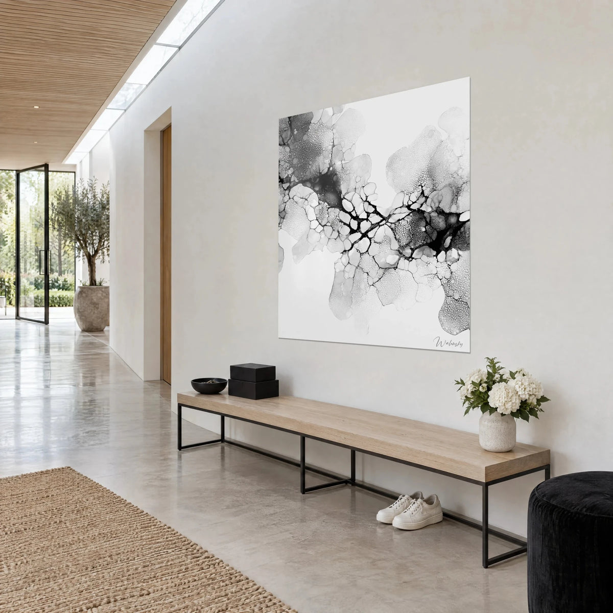 Wall art with abstract ink in shades of grey, branching black veins on white, hung above a wooden bench in a light hallway